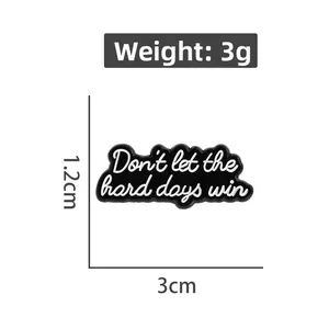 Detail view of monochrome enamel pin with inspirational quote measuring 3cm by 1.2cm