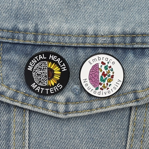 Pins émaillés Mental Health Matters et Neurodiversity sur veste en jean bleue