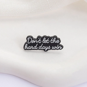 Detail of enamel pin featuring white hand-lettered text Don't let the hard days win