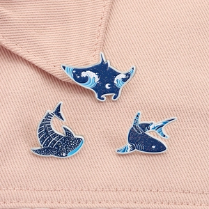 Macro detail of three blue enamel marine animal brooches on a soft textured background