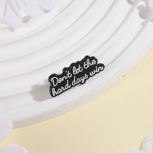Close-up of black enamel cloud pin with white Don't let the hard days win quote
