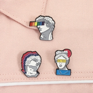 Close-up of retro statue enamel pins with rainbow art patterns on pink denim fabric