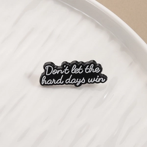 Minimalist black and white enamel pin featuring 'Don't let the hard days win' quote