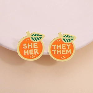 Creative orange enamel pins set with she/her and they/them pronouns in gold finish
