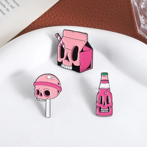 Roze gothic emaille speldjes met schedel, melkpak en lolly op een wit keramisch bord