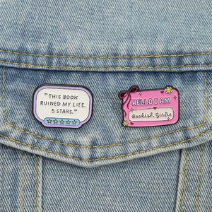 Enamel pins with humorous bookish text pinned on a blue denim jacket pocket