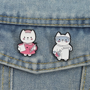 Close-up of nurse and scientist cat enamel pins pinned to a blue denim jacket pocket