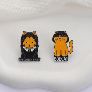 Orange bobcat and Halloween spirit enamel pin set on a clean white display board