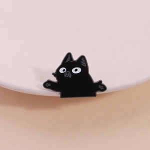Funny black cat enamel pin with shrug pose and large eyes on a warm beige background