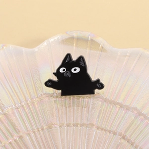 Macro d'une broche en émail chat noir rigolo dans un plateau en nacre en forme de coquillage