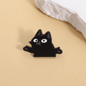 Détail d'un pin's chat noir de dessin animé sur fond beige avec une pierre décorative