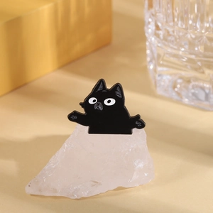 Gros plan d'une broche chat noir en émail sur un support de cristal blanc décoratif