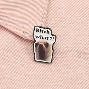 Close-up of Funny Chihuahua Meme Enamel Pin with 'Bitch what?!' text on pink fabric