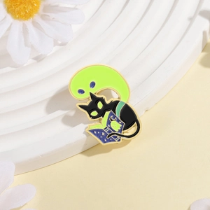 Macro detail of enamel brooch showing black cat reading a magic book with green ghosts