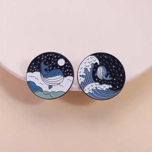 Enamel whale pins set featuring waves and starry sky patterns on a minimalist display