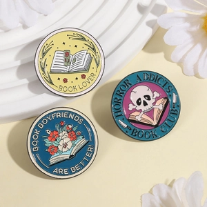 Three-piece set of book-themed round enamel pins with floral and skull motifs