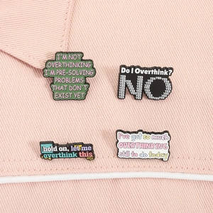 Dettaglio di quattro spille in smalto colorato con citazioni umoristiche Overthinking