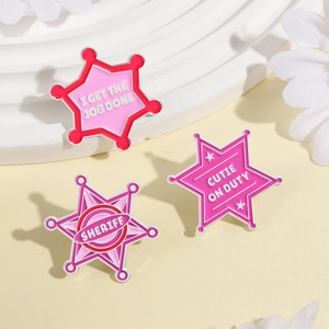 Set of three pink enamel star pins with motivational slogans on a white minimalist display