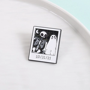 Polaroid style enamel pin featuring a skeleton and ghost design with glitter for Halloween