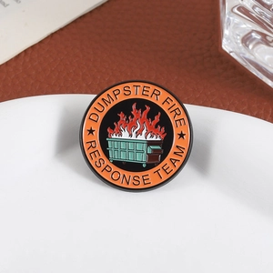 Vue rapprochée du pin's émaillé Dumpster Fire Response Team sur un plat blanc