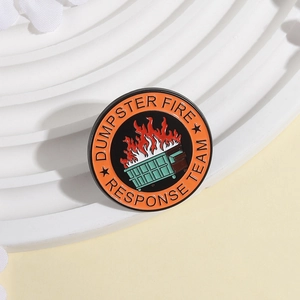 Détail d'un badge en métal avec le texte Dumpster Fire Response Team et icône cartoon