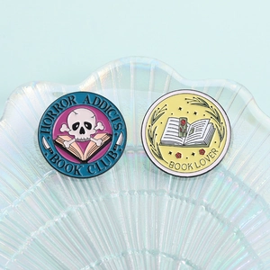 Close-up of enamel pins featuring Horror Addicts Book Club and Book Lover designs
