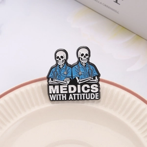 Cartoon skeleton doctors enamel pin with Medics With Attitude text on ceramic plate