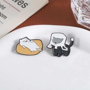 Cute enamel cat pins featuring a white cat on beanbag and a black cat with collar