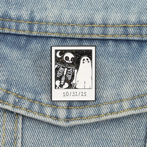 Detail of Halloween enamel pin with skull and ghost on a blue denim jacket pocket