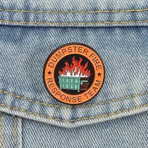 Détail macro d'un pin's émaillé Dumpster Fire fixé sur la poche d'une veste en jean