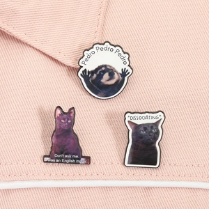 Détail des pin's émaillés chat et raton laveur meme sur tissu sergé rose pastel