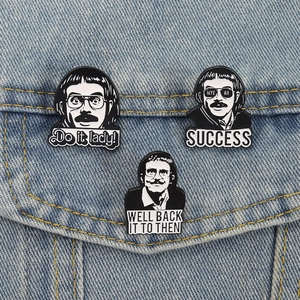 Three retro black and white enamel pins with quirky avatars on denim jacket