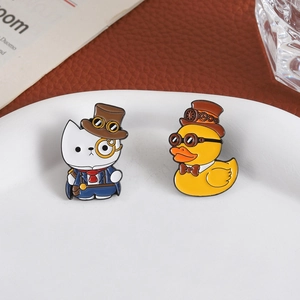 Steampunk cat and duck enamel pins set on a tray with vintage books and leather