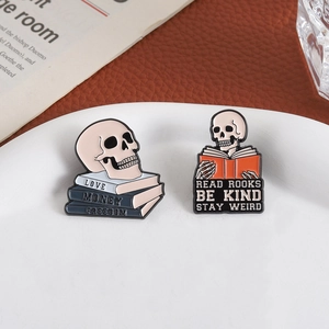 Artistic skull reading book enamel pins set on a white ceramic plate with a stylish background