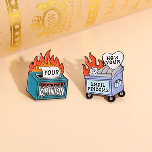 Macro shot of Dumpster Fire and Shredder enamel pins with creative slogan engravings