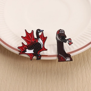 Set of two Canada Goose enamel pins featuring a red maple leaf and flag on a ceramic dish