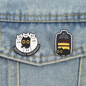 Cute enamel cat pins featuring Socially Awkward and Social Battery designs on denim jacket