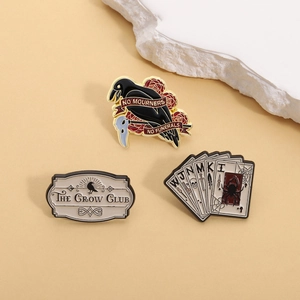 Dettaglio spillette smaltate con corvo, placca The Crow Club e carte da gioco
