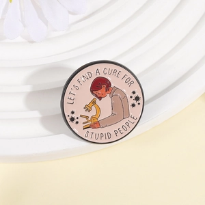 Round enamel science brooch with microscope and 'Let's Find a Cure for Stupid People' text