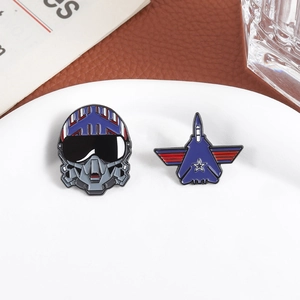 Fighter jet and pilot helmet enamel pins set on a decorative white ceramic tray