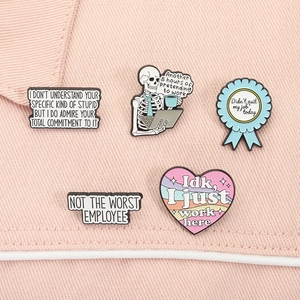 Detailed view of five workplace humor enamel pins displayed on pink denim fabric material