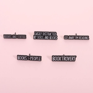 Five minimalist enamel book lover pins with quotes on a soft pink background