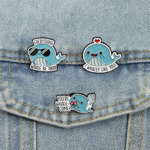 Three-piece set of cartoon blue whale enamel pins on denim fabric with cute puns