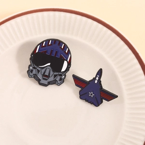 Enamel pilot helmet and blue fighter jet brooch set displayed on white ceramic plate