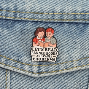 Retro enamel brooch with boy and girl reading books on blue denim fabric jacket