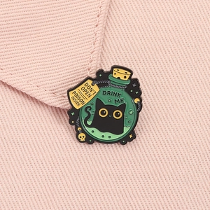 Macro detail of enamel black cat poison bottle pin on pink fabric background