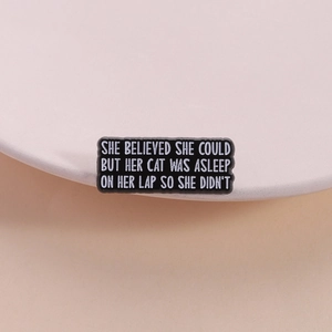 Funny black enamel cat pin featuring 'She believed she could but her cat was asleep' text