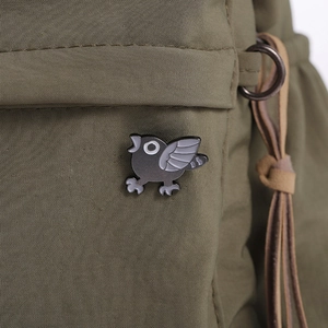 Close-up of a punk bird enamel pin attached to a green nylon fabric backpack strap