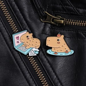 Detail view of two cute capybara enamel pins on black leather jacket with gold zipper