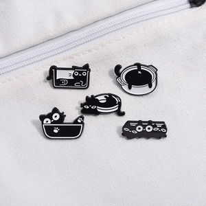 Lot de cinq broches créatives en émail chat noir et blanc épinglées sur toile blanche